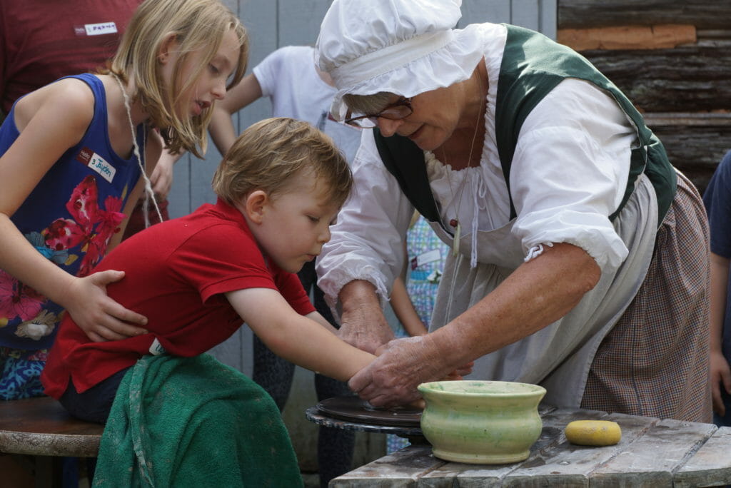 a child and adult making pottery