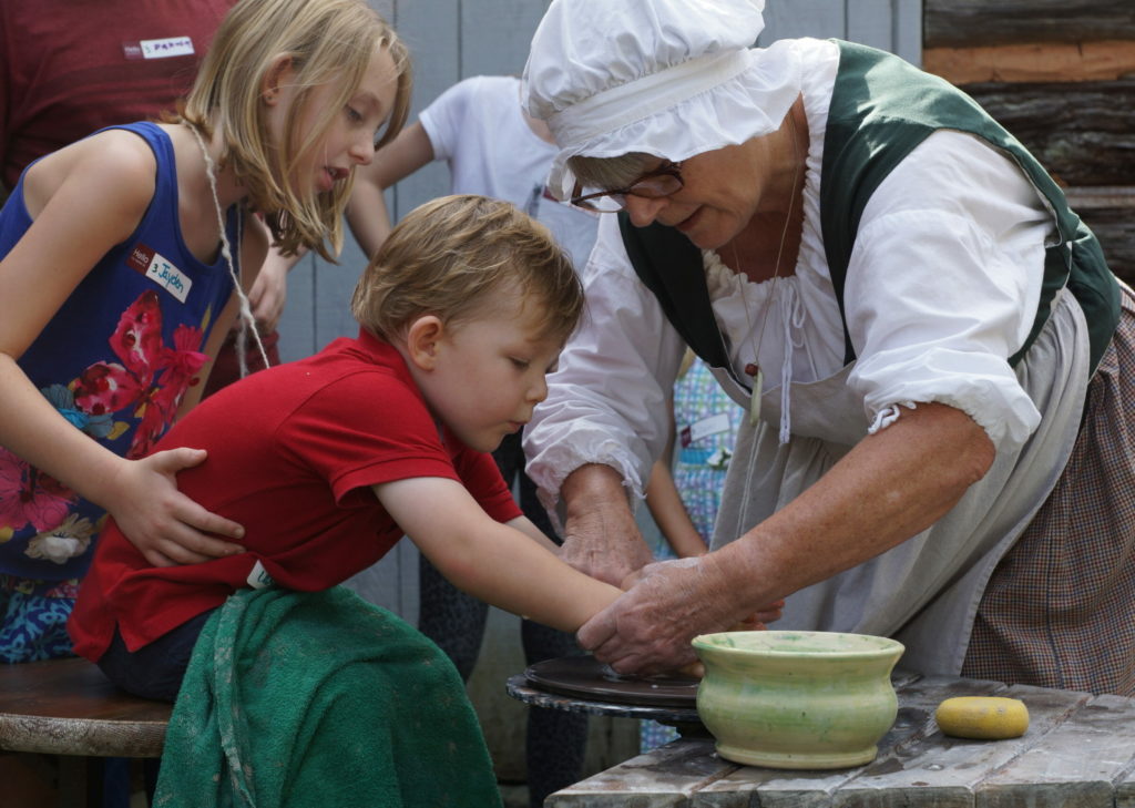 a child and adult making pottery